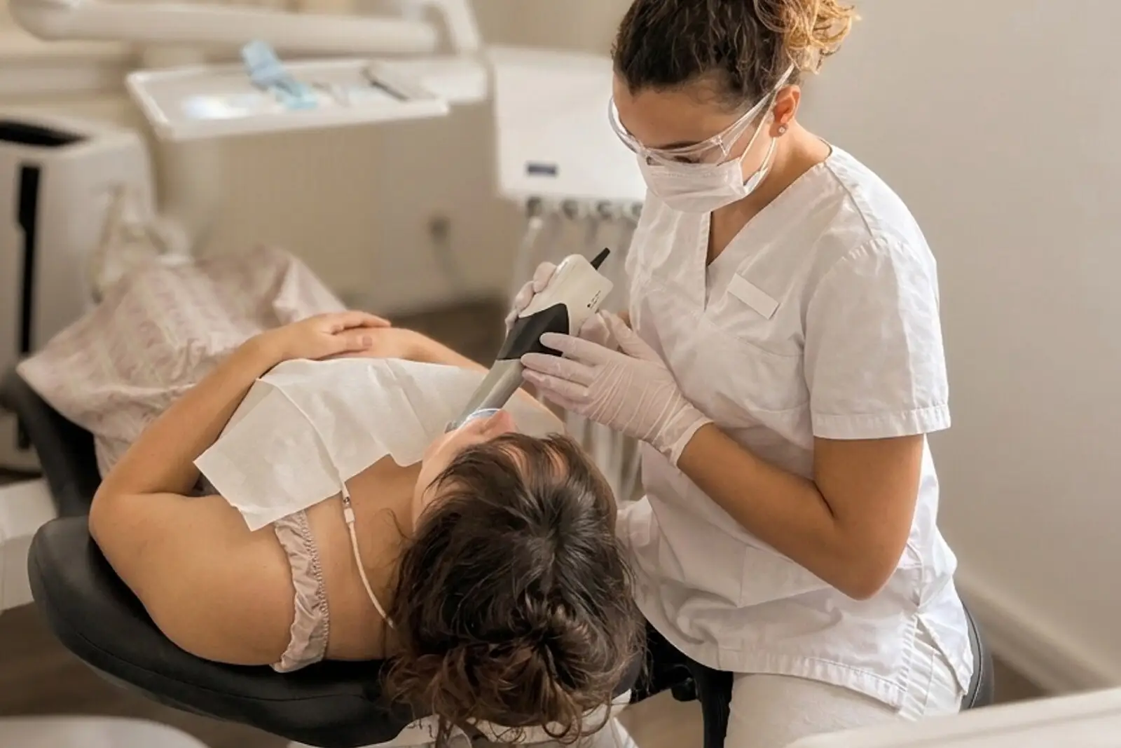 Mitarbeiterin erfasst die Zähne einer Patientin mit dem Intraoralscanner.