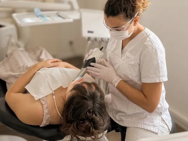 Mitarbeiterin erfasst die Zähne einer Patientin mit dem Intraoralscanner.